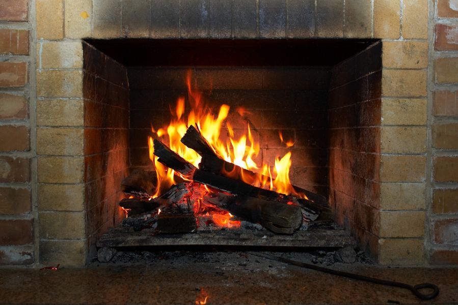 Cheminée traditionnelle en fonctionnement avec des bûches en train de brûler, illustrant les risques de formation de bistre et de créosote lors de la combustion du bois.